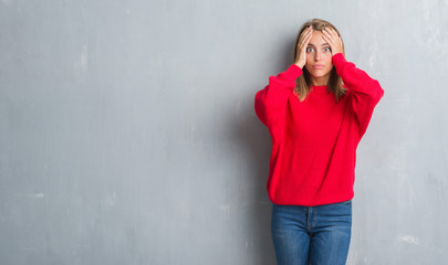 Obraz na płótnie Canvas Beautiful young woman standing over grunge grey wall wearing winter sweater stressed with hand on head, shocked with shame and surprise face, angry and frustrated. Fear and upset for mistake.