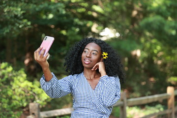 Stylish ethnic woman with phone in park