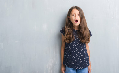 Young hispanic kid over grunge grey wall afraid and shocked with surprise expression, fear and excited face.