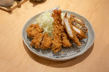 Deep fried meat cutlet coated with flaky panko bread crumb and stuffed with cheese, Tonkatsu over metal sieve and shredded cabbage.