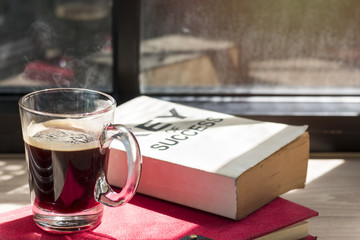 Business of success book and black coffee on wood near window in light morning.Copy space.