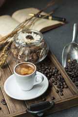 Espresso cup,coffee bean,book and dried flowers jar on wooden tray with warm morning light near the window.Copy space.