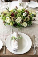 Neatly twisted into a tube dining room napkin decorated with a sprig of pistachio. Wedding Banquet or gala dinner. The chairs and table for guests, served with cutlery and crockery. party on terrace