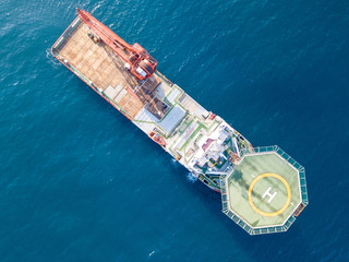 Aerial image of a Medium size red Offshore supply ship with a Helipad and a large crane