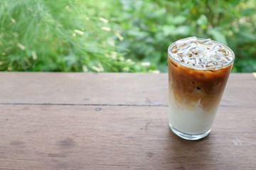 High angle view of iced cafe latte coffee on a wooden table in a cafe with green background 
