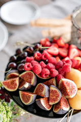 Fresh Fruit platter on banquet table at business or wedding event venue. Self service or all you can eat - raspberry, strawberry, cherry, Fig, apricote. Table with cold snacks and tableware