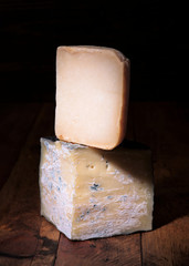 pieces of cheese in dark ambience on rustic wooden board