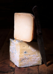 pieces of cheese in dark ambience on rustic wooden board