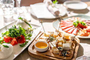 Cheese plate. Delicious cheese mix with walnuts, honey on wooden table. Tasting dish on a wooden plate. Food for wine.