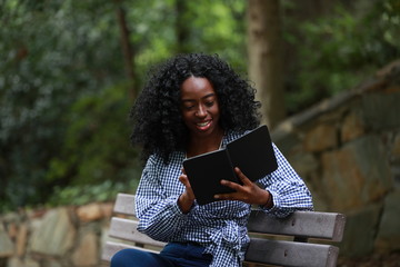 Content black woman enjoying reading on bench
