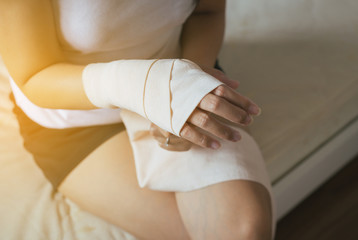 Obraz na płótnie Canvas Woman using elastic bandage with hand,Female putting bandage on her injured hands