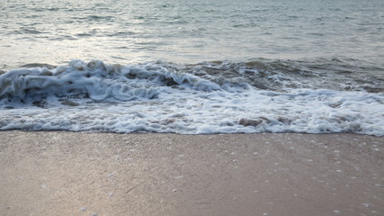 Sand beach with sea waves in the sunset.