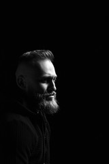 Black and white male portrait with a beard on a black background