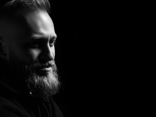 Black and white male portrait with a beard on a black background
