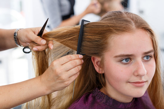 Hands of hairdresser making hairstyle for girl