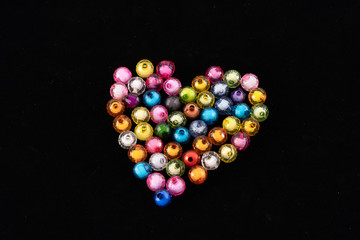 Beads, colorful beads on a black background, arranged a heart shape.