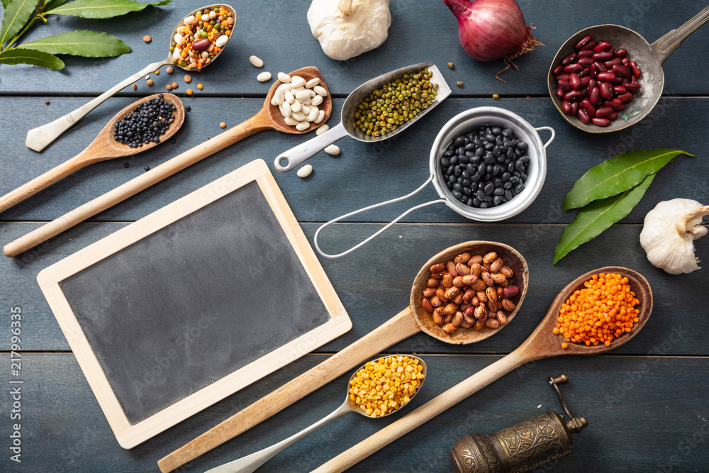 Canvas Prints Top view of flat lay of assortment of legumes pulses on black wooden tabletop, in scoop and ladles and a small blackboard