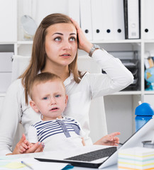 Perplexed mom with kid is having issue while working behind laptop