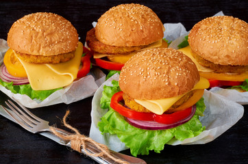 Vegetarian burgers with falafel, salad, onion rings, cheese and tomatoes on the black background. Traditional Middle Eastern fast food. Close up view