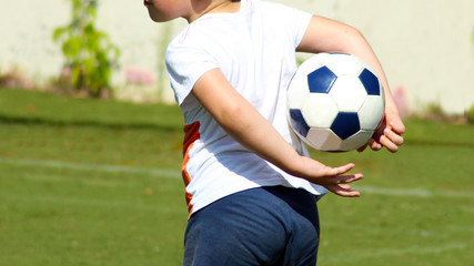 Boy holding a soccer ball behind his back