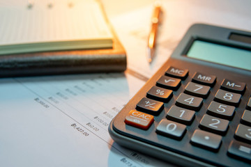 Calculator, pen, blank lined paper page of notebook and summary report paperwork with bar graph and table. Financial data analysis. Business planning and management concept
