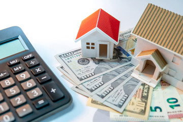 Real estate or property development. Construction business investment concept. Home mortgage loan rate. House models on dollar and euro banknotes with calculator on the table.
