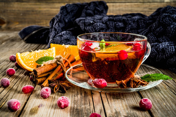 Autumn winter hot drink, cranberry spicy tea with orange, cinnamon and anise. On an old wooden...