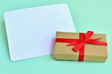 Gift box tied with a red ribbon, white blank, greeting card. 