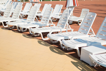 White loungers near the swimming pool on a summer day.