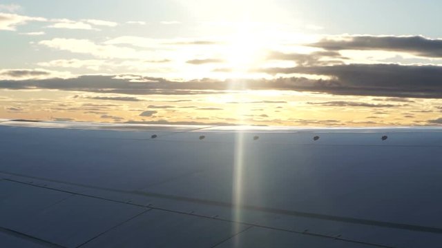 Plane wing flying over morning sunrise reflect cloud slow motion video
