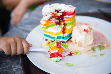 Rainbow cake and vanilla ice cream in a beautifully decorated white dish.