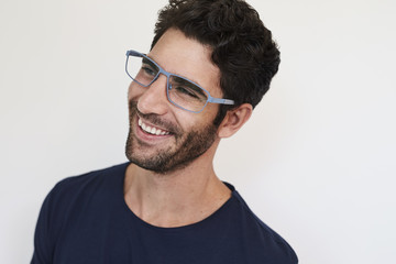 Obraz premium Smiling stubble guy in glasses, looking away
