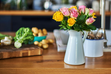 Vase of roses on blurred rustic kitchen background.