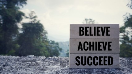 Motivational and inspirational quote - ‘BELIEVE, ACHIEVE, SUCCEED’ written on wooden blocks....