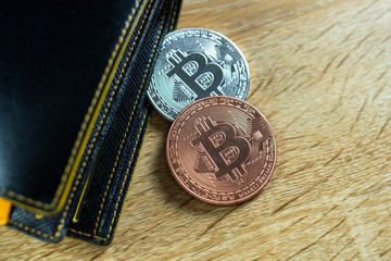 Bitcoin digital currency instead real money, bit-coin with leather wallet or purse on wooden working table, virtual cryptocurrency money business concept.