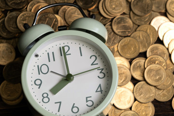 Alarm clock and coins stacks on working table in dark room, time for savings money concept, banking and business concept.