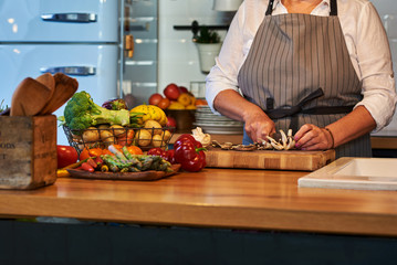 Elderly woman's hands cutting vegetables. Kitchen scene with various vegetables.
