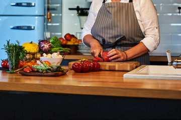 Preparing vegetables salad. Senior woman cutting tomatoes. Hands are in focus.