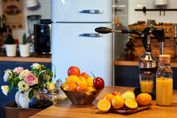 Arrangement of fresh fruit and the manual juicer on a old rustic kitchen table.