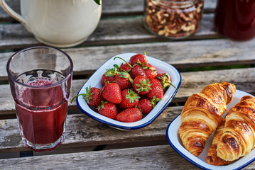 Homemade croissants, fresh berries,  and  juice for breakfast on dark wooden background. Health and diet concept..