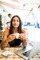 Young latin woman using laptop computer in a cafe while drink cup of coffee in the morning or at break