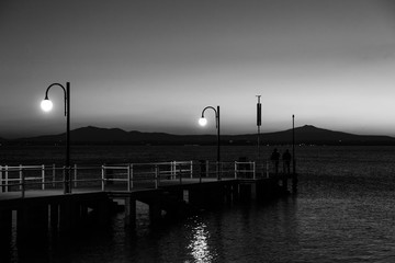 Some people on a pier at Trasimeno lake (Umbria, Italy) at dusk