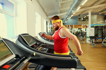A funny fat man with a beard doing exercises in the gym.