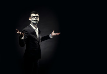 Portrait of man with Halloween skull makeup on the black background.