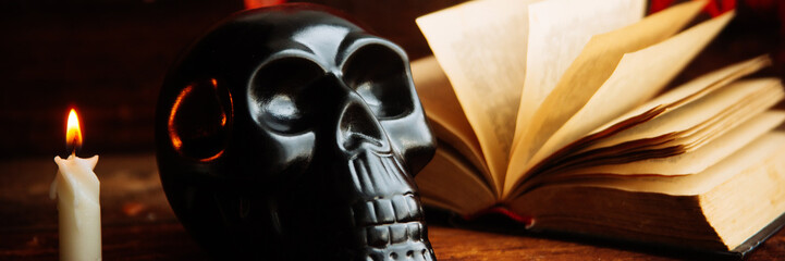 Halloween concept with a pumpkin,skeleton,candles and toy spider on a cobweb wood background, banner, long wide