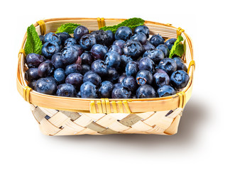 Fresh and raw blueberries in a small wicker basket. Isolated and on white background.