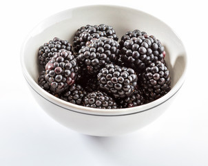 Delicious fresh blackberries and ripe black and reddish garnet. In white bowl and isolated background.