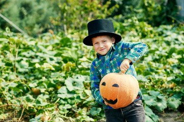 Funny boy with pumpkin on Halloween . The boy is preparing for the holiday Halloween