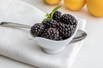 Delicious fresh blackberries and ripe black and reddish garnet. In white bowl and isolated background. With apricots.