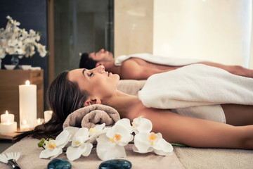 Young man and woman lying down on massage beds at Asian luxury spa and wellness center